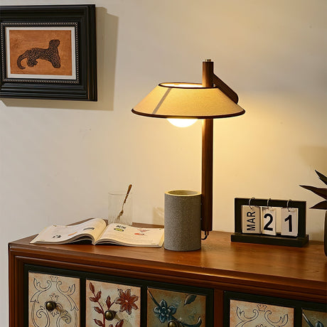 Cement base lamp lit warm against a pale wall above an open book