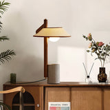 Cement base lamp lit on a sideboard beside a reed diffuser and flowers