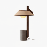 Table lamp with a flat wood post on a cement cylinder and a wide shade