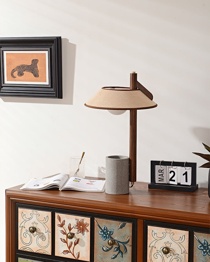 Cement base lamp lit on a cabinet below a small framed print