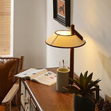 Cement base lamp lit on a cabinet beside a plant and an open book