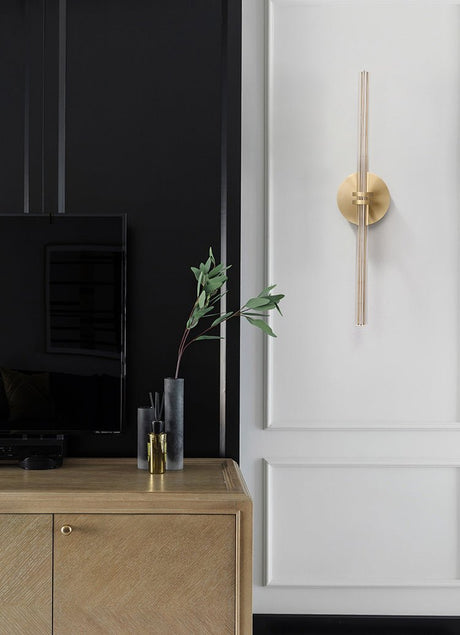 Rod lit upright on a kitchen wall beside a wood cabinet and a small vase