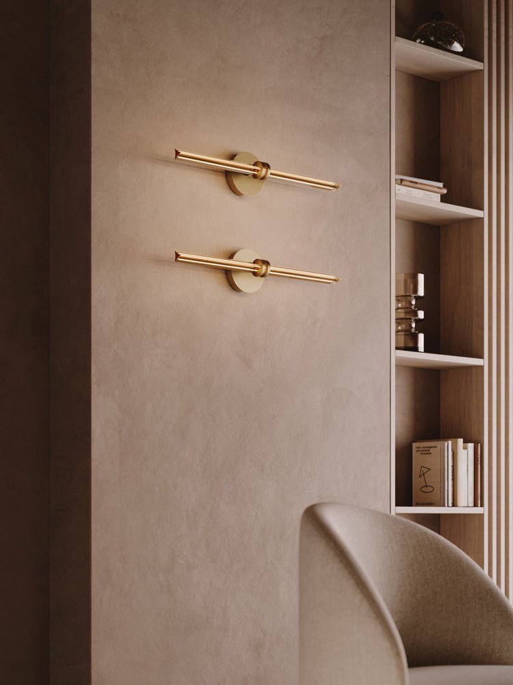 Two rods lit one above the other on a plaster wall beside shelving and a chair