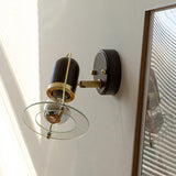 Sconce unlit beside a tall wood mirror frame and a blind in a pale room