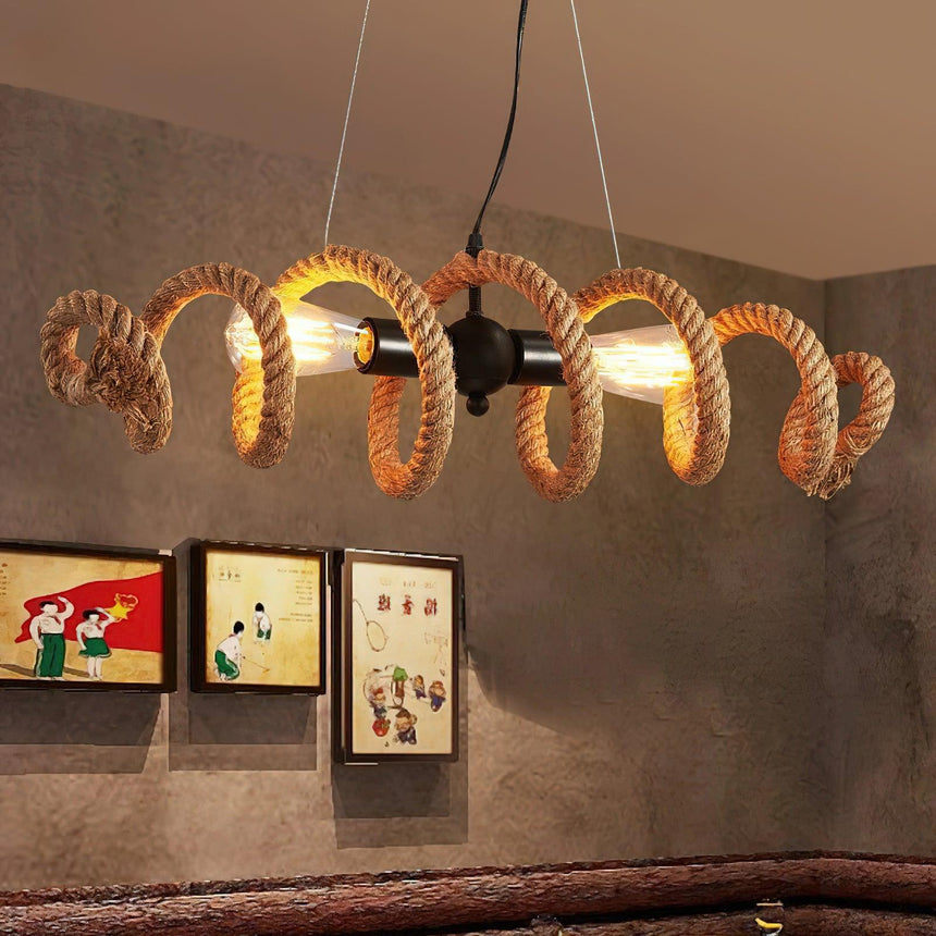 Coiled rope fitting lit on a plaster wall beside two framed prints