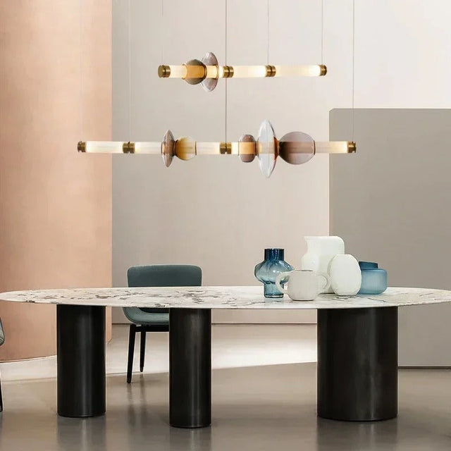 The gold linear bar lit above a long dining table with pale chairs