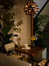 Chandelier lit beside a tall plant above a table and a cup