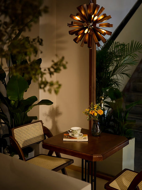 Chandelier lit beside a tall plant above a table and a cup