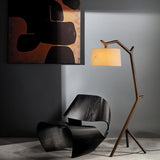 The lit lamp beside a black molded chair with abstract artwork on the wall behind