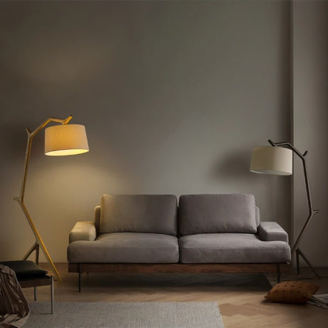 Two of the lamps, one light wood and one dark, standing at each end of a sofa