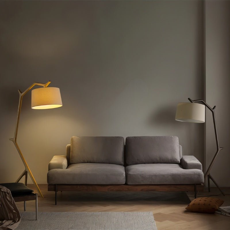 Two of the lamps, one light wood and one dark, standing at each end of a sofa