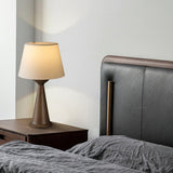 Japandi table lamp lit on a nightstand beside a leather headboard