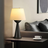 Black based Japandi table lamp lit on a console beside a dark sofa