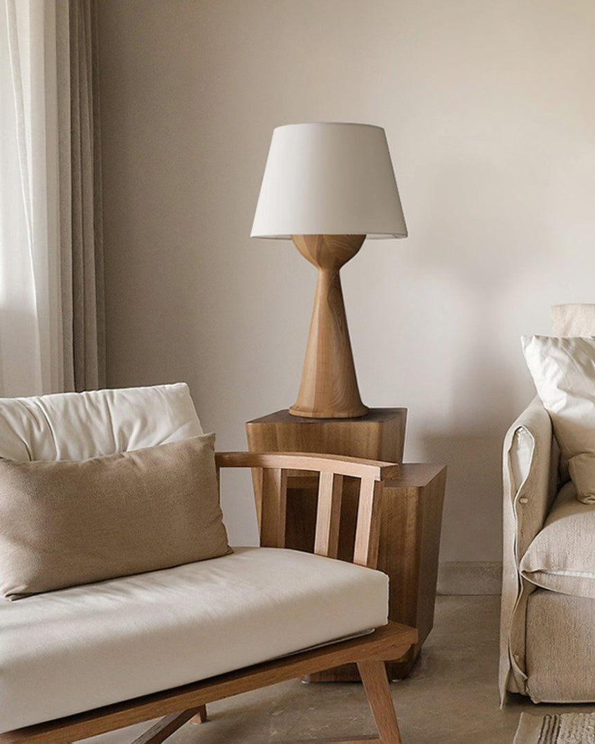 Japandi table lamp lit on a side table beside a pale armchair