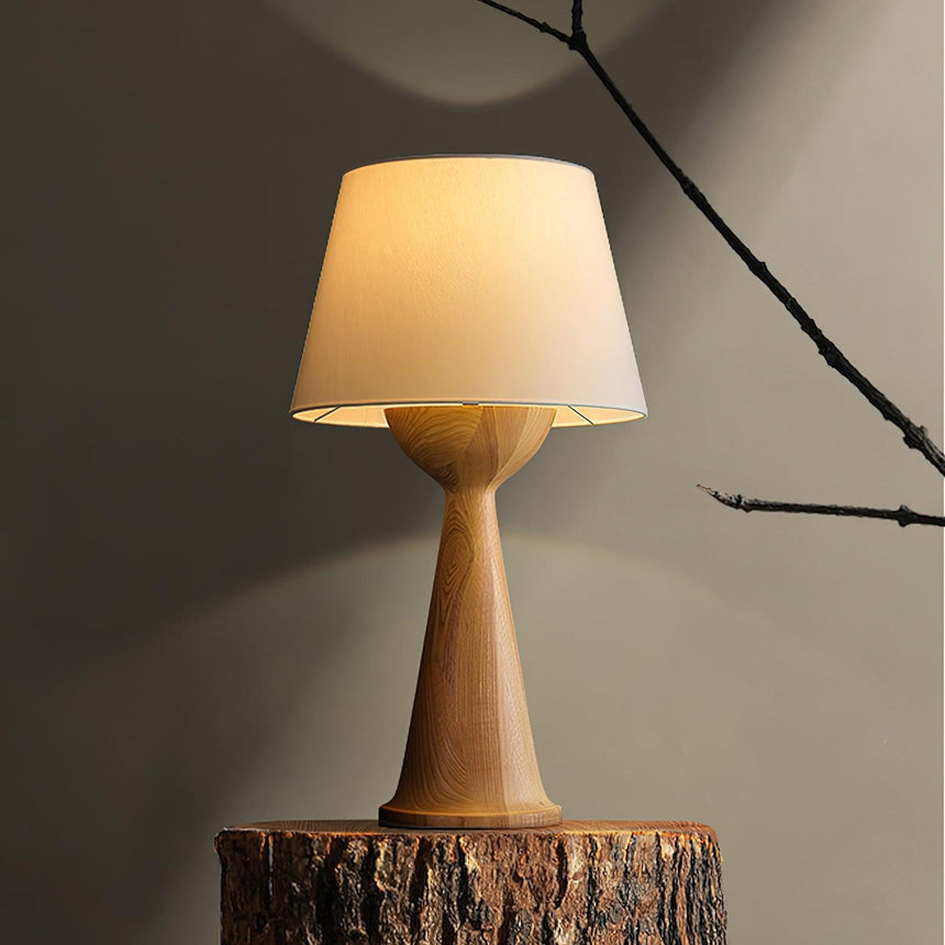 Japandi table lamp lit on a cut tree stump against a warm wall
