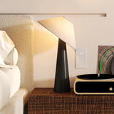 Black tilted shade table lamp lit on a woven bench against a wall