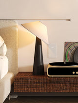 Black tilted shade table lamp lit on a bench beside a record player