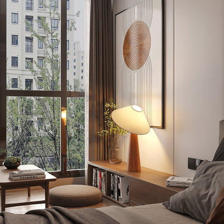 Tilted shade table lamp lit on a low table in a bedroom by a window