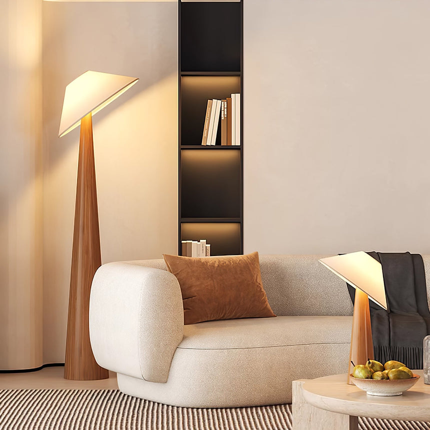Tilted shade table lamp lit on a side table beside a cream armchair