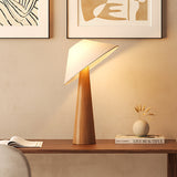 Tilted shade table lamp lit on a console below two framed prints