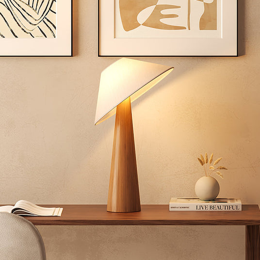 Tilted shade table lamp lit on a console below two framed prints