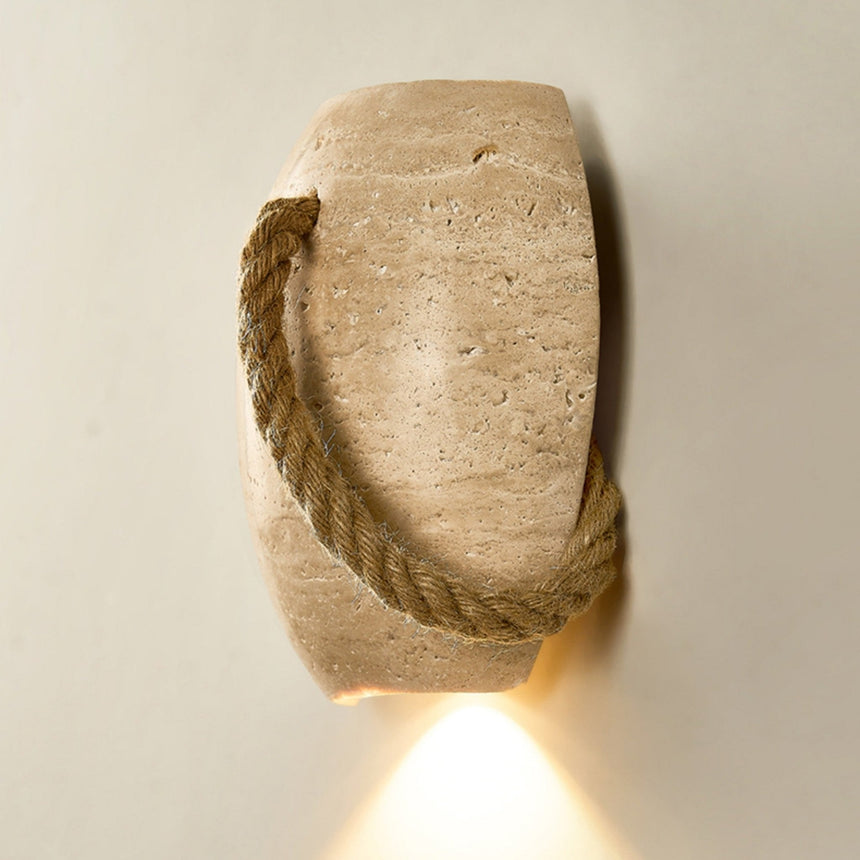 Close front view of the travertine surface and the twisted hemp rope, lit from below