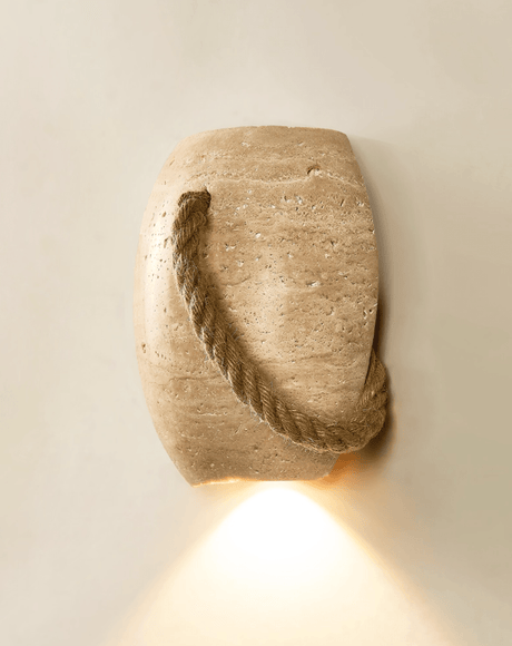 The urn lit on a cream wall, a cone of warm light falling from its open base