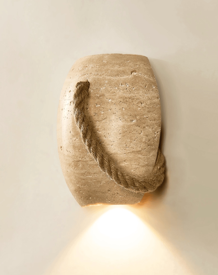 The urn lit on a cream wall, a cone of warm light falling from its open base
