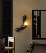 Sconce lit beside a mirror above a console with a wood chair below