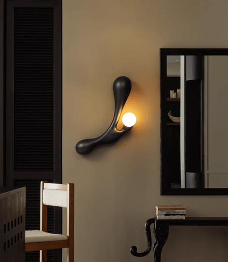 Sconce lit beside a mirror above a console with a wood chair below