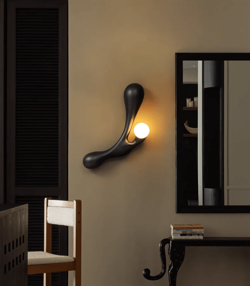 Sconce lit beside a mirror above a console with a wood chair below
