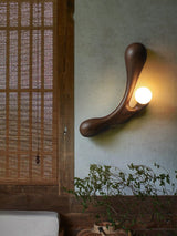 Sconce lit on a plaster wall beside a wood screen and a climbing plant