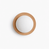 The pale wood ring lit close, the frosted ball glowing inside the frame
