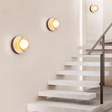 Two sconces lit on a wall beside a run of pale stone stairs