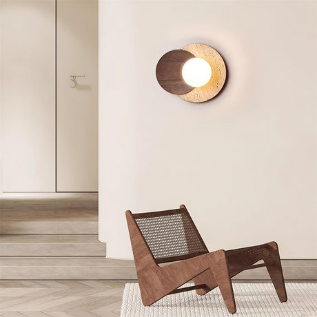 Sconce lit in a hallway above a woven wood chair on a pale floor