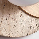Close view of the porous travertine surface beside the glass orb