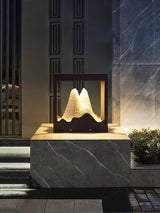 The frame glowing on a low wall beside dark garden steps at night