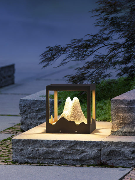 The lit mountain on a stone planter beside clipped garden planting