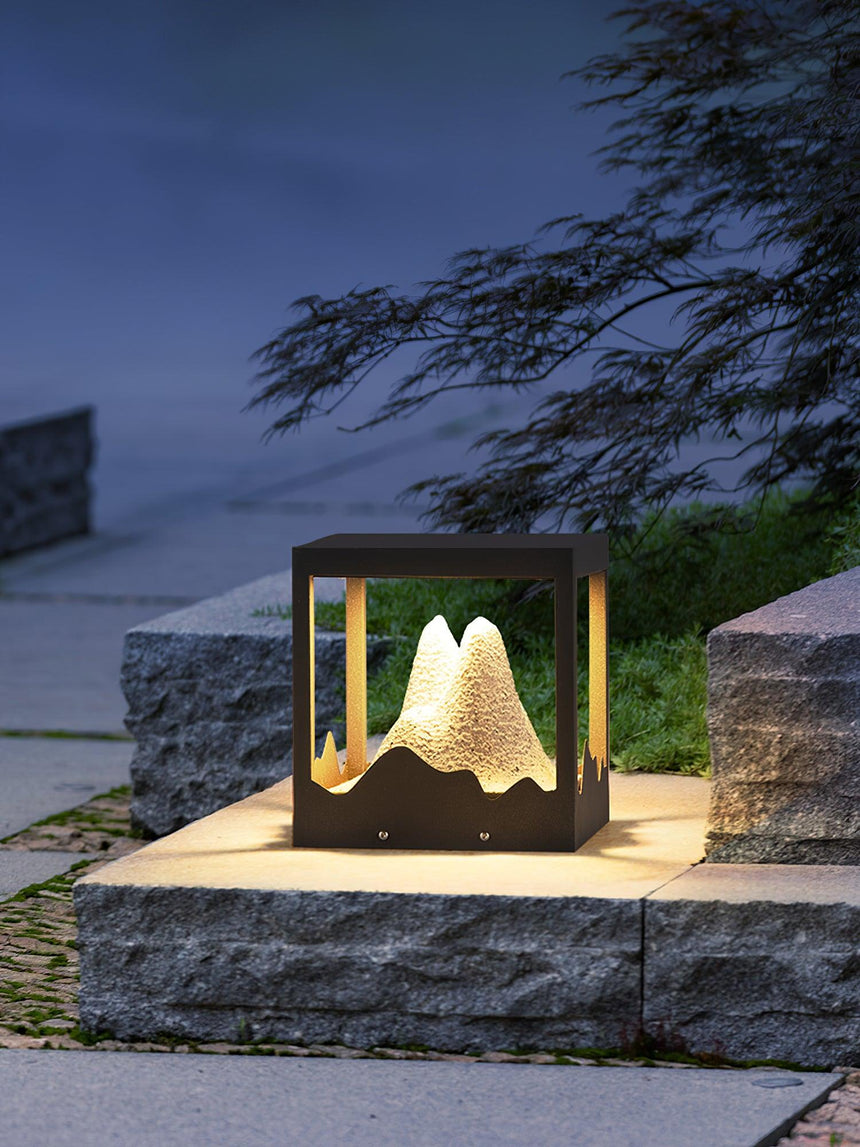 The lit mountain on a stone planter beside clipped garden planting