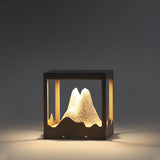 The resin peak lit warm inside its frame against a dark garden