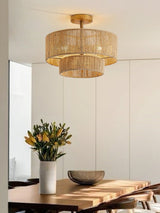 Two tier jute ceiling light above a dining table with yellow tulips in a vase
