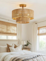 Two tier jute ceiling light above a bed with woven blinds and layered bedding