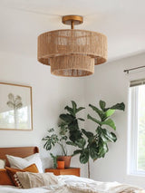 Jute ceiling light lit in a bedroom with a large plant and a leather bench