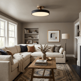 Black drum ceiling light in a living room with a sectional sofa and shelving