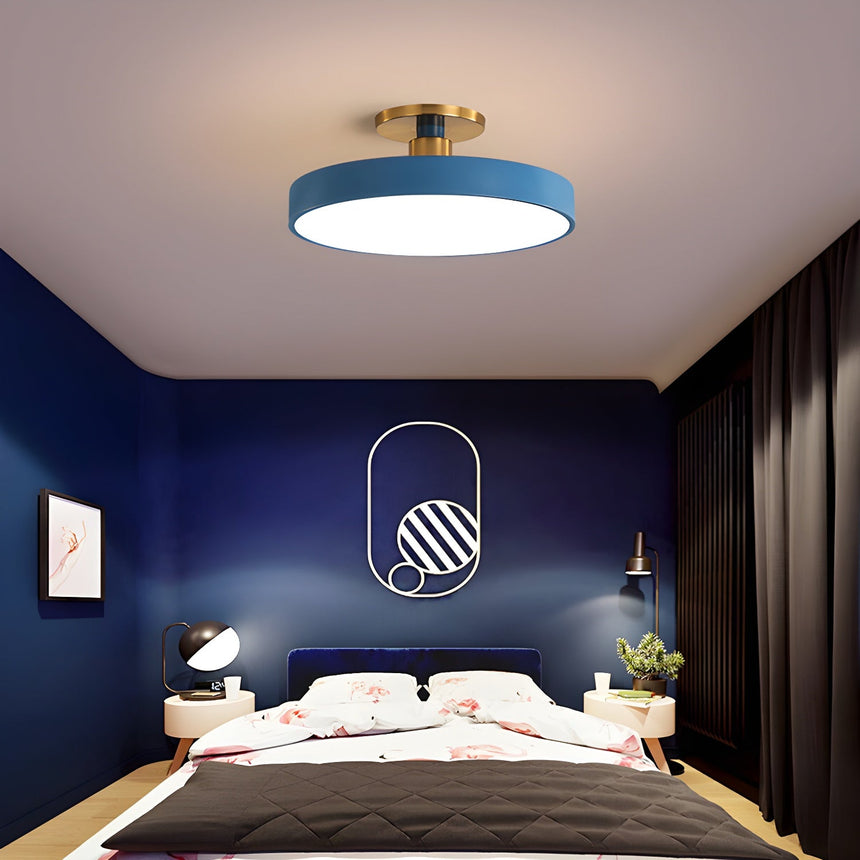 Blue drum ceiling light above a bed in a room with navy walls