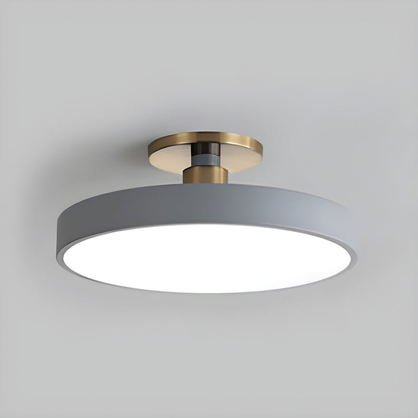 Gray drum ceiling light with a brass stem seen at an angle