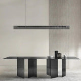 The slim lit bar hung above a long stone dining table in a bare room