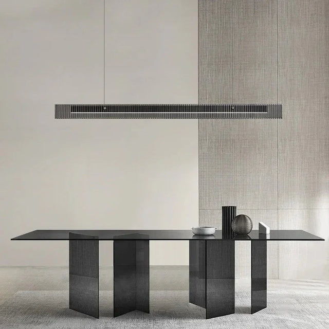 The slim lit bar hung above a long stone dining table in a bare room