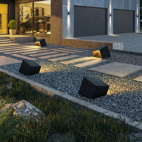 Several lit along a gravel strip and a paved walk beside a garage