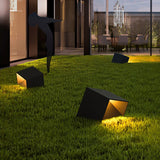 Two lit on a lawn with a lit house wall and planting behind them